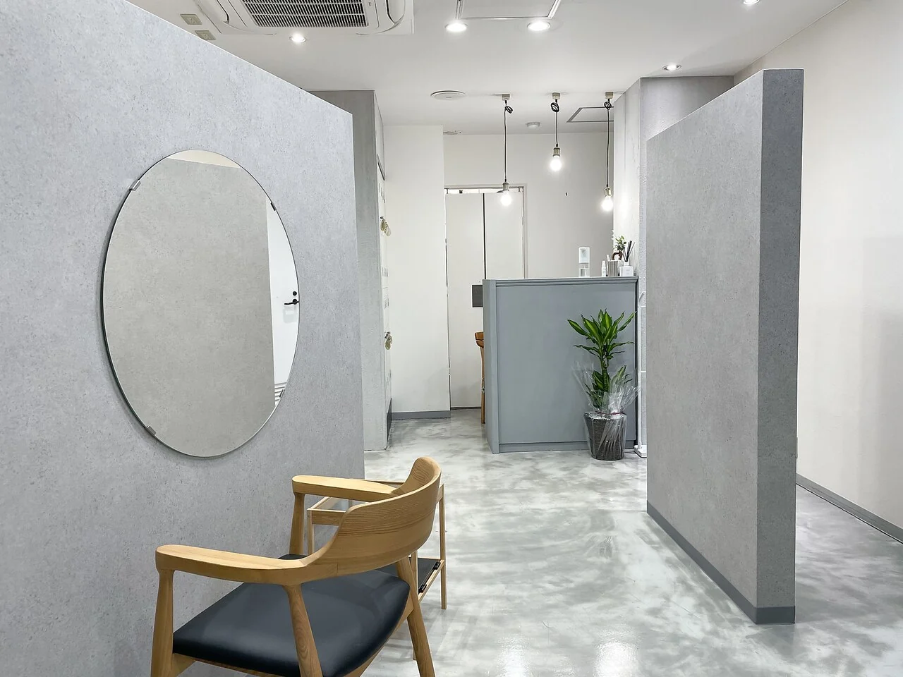 丸い鏡とグレーの間仕切りが並ぶ、Lune.梅田の落ち着いた店内